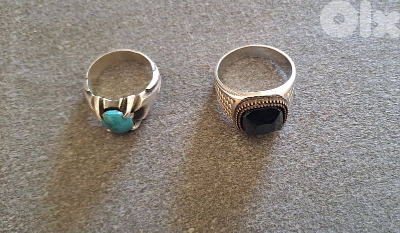 2 rings; 1st a silver ring with a turquoise gemstone,2nd with a black. 0